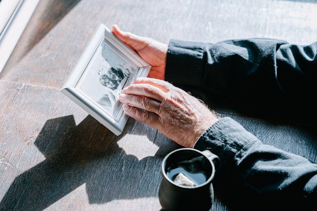 Man looking at a photo of wife depicting the loss of a loved one and grief.