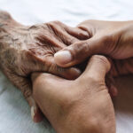 Alzheimer elderly holding the hand of a son or daughter