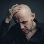 The man in the photo is dealing with sudden loss by his expression