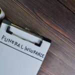 Funeral Insurance write on sticky notes isolated on Wooden Table.