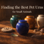 Colorful handcrafted pet cremation urns in jewel tones displayed with a feather, paw print, and snakeskin memorial elements representing urns for birds, small mammals, and reptiles