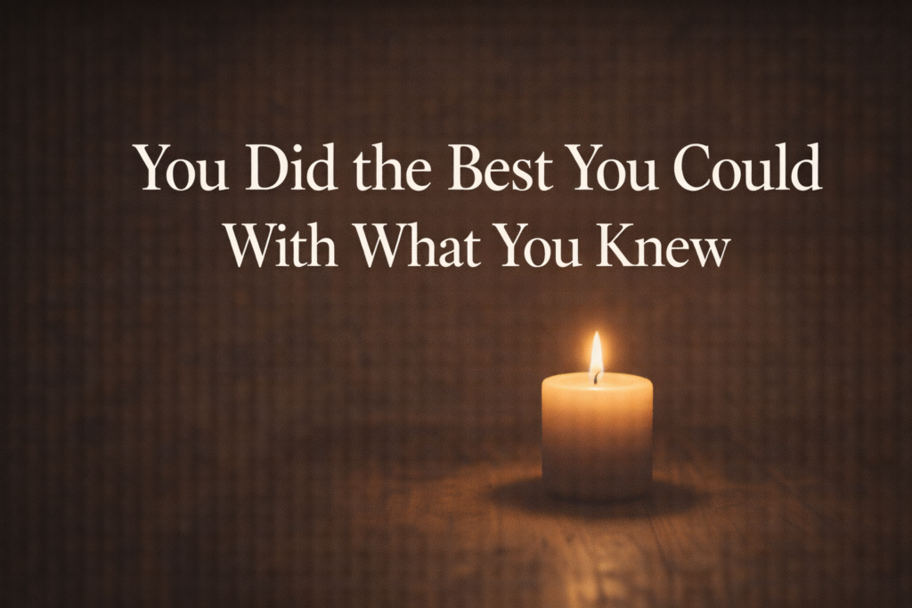 Single candle burning in a dark room with a warm glow, representing the process of releasing guilt and practicing self-compassion during grief