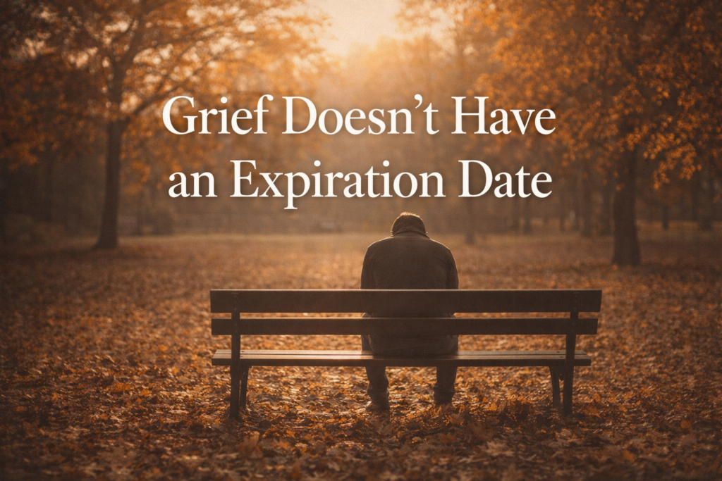 Person sitting alone on a park bench in autumn light, representing the isolation of grief when others stop understanding