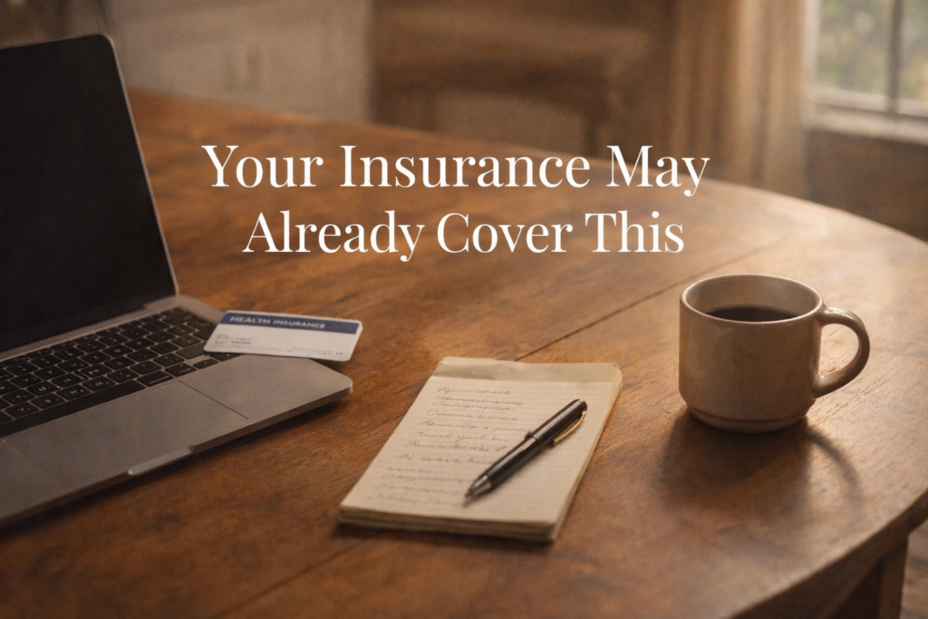 Kitchen table with laptop, insurance card, and notepad suggesting someone researching grief therapy insurance coverage from home