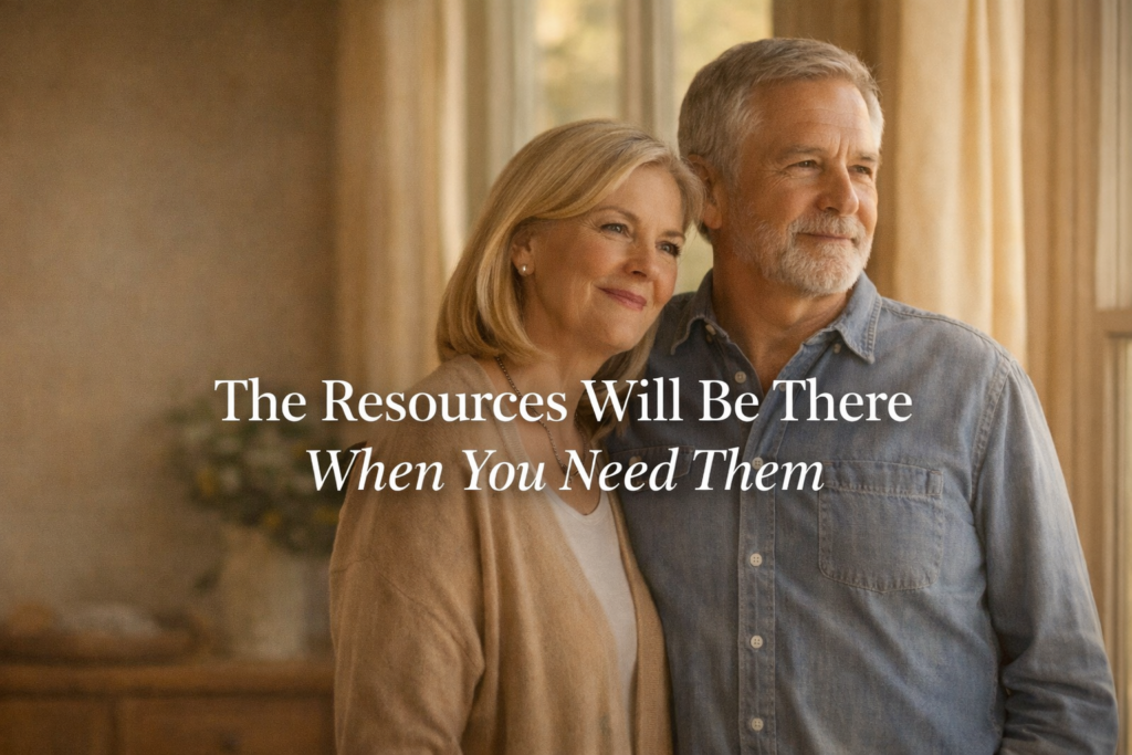 Couple in their early 60s standing together near a window in warm afternoon light, calm and forward-looking